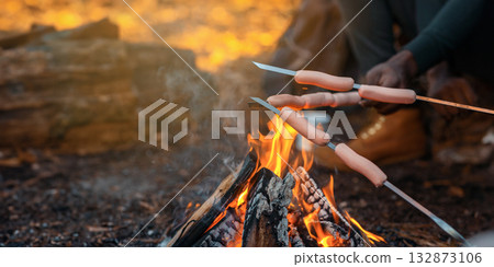 Hands of international, hikers frying sausages, camping in forest, closeup, copy space 132873106