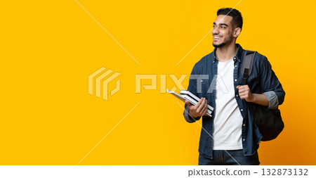 Positive arab guy student with backpack and bunch of books looking at copy space for advertisement over yellow studio background, panorama. Education, university, college, studying, course concept Positive arab guy student with backpack and bunch of books looking at copy space for advertisement over yellow studio background, panorama. Education, university, college, studying, course concept 132873132