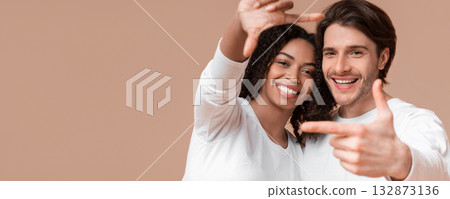 Capturing Happy Moment. Romantic Multiracial Couple Framing Their Faces With Fingers nd Sincerely Laughing, Posing Together On Yellow Background 132873136