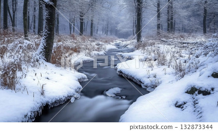 A peaceful winter scene features a gently flowing stream winding through a dense forest. Snow blankets the trees and ground, creating a tranquil atmosphere during twilight hours. A peaceful winter scene features a gently flowing stream winding through a dense forest. Snow blankets the trees and ground, creating a tranquil atmosphere during twilight hours. 132873344