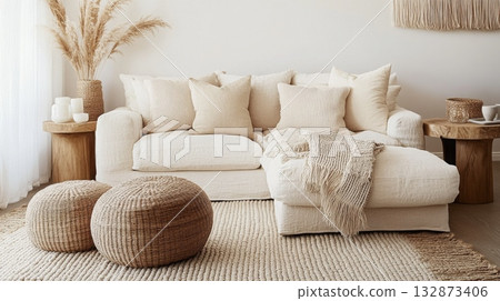 A serene living room features a plush white sofa adorned with soft pillows, complemented by woven furniture and decorative elements, creating a warm and inviting atmosphere. 132873406