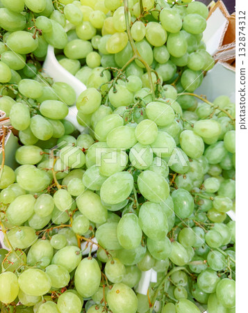 A vibrant display of fresh green grapes arranged in a cluster. Their natural color and plump appearance emphasize freshness and quality, making them ideal for food and beverage stock images. A vibrant display of fresh green grapes arranged in a cluster. Their natural color and plump appearance emphasize freshness and quality, making them ideal for food and beverage stock images. 132874312