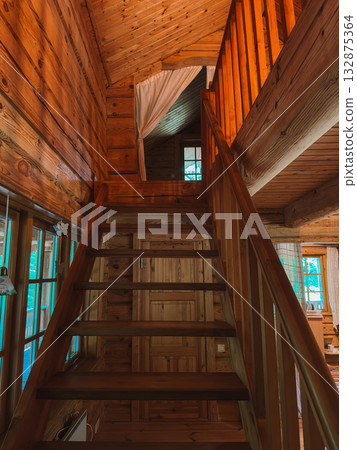 Low-angle view of a wooden staircase inside a rustic log cabin 132875364