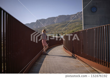 Woman modern rusty walkway blonde woman gazing at vast green mountain landscape 132876192