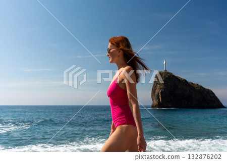 Woman Beach Crimea: Summer strolls on sunny Black Sea coast near a rock with cross monument. 132876202