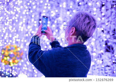 A man taking a photo of illuminations 132876269