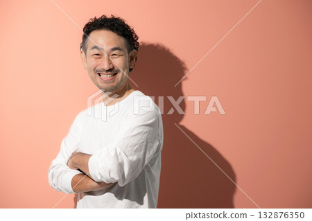 A middle-aged man with a refreshing beard crossing his arms against an orange background 132876350