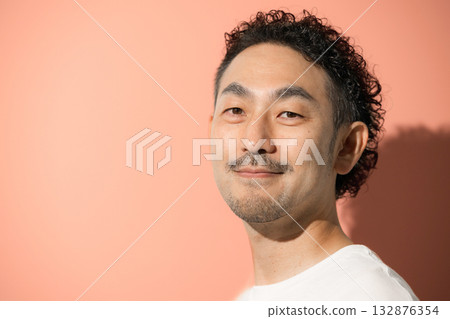 Close-up of a middle-aged man with a beard looking at camera against an orange background 132876354