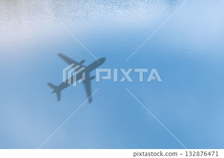 Concept of airplane travel. Airplane shadow on blue water. 132876471