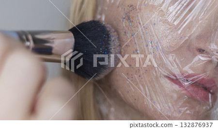 Microplastics in cosmetics. A woman applied a care cream to her skin, now it is covered with plastic particles and microbeads. Cosmetics toxicity concept 132876937