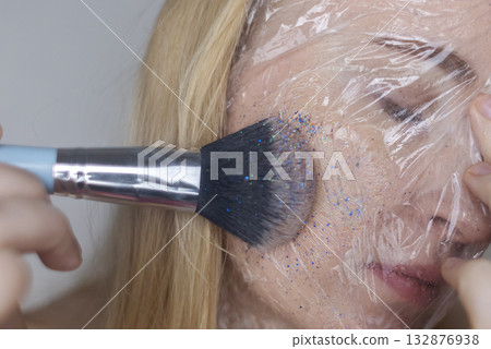 Microplastics in cosmetics. A woman applied a care cream to her skin, now it is covered with plastic particles and microbeads. Cosmetics toxicity concept 132876938