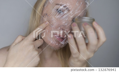 Microplastics in cosmetics. A woman applied a care cream to her skin, now it is covered with plastic particles and microbeads. Cosmetics toxicity concept 132876941