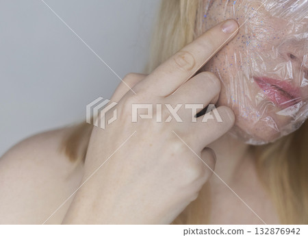 Microplastics in cosmetics. A woman applied a care cream to her skin, now it is covered with plastic particles and microbeads. Cosmetics toxicity concept Microplastics in cosmetics. A woman applied a care cream to her skin, now it is covered with plastic particles and microbeads. Cosmetics toxicity concept 132876942