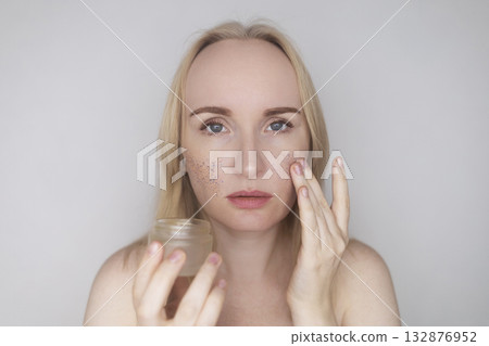 Microplastics in cosmetics. A woman applied a care cream to her skin, now it is covered with plastic particles and microbeads. Cosmetics toxicity concept 132876952