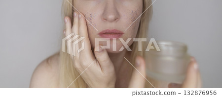 Microplastics in cosmetics. A woman applied a care cream to her skin, now it is covered with plastic particles and microbeads. Cosmetics toxicity concept Microplastics in cosmetics. A woman applied a care cream to her skin, now it is covered with plastic particles and microbeads. Cosmetics toxicity concept 132876956
