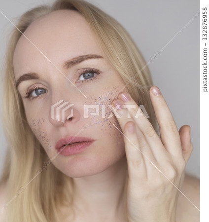 Microplastics in cosmetics. A woman applied a care cream to her skin, now it is covered with plastic particles and microbeads. Cosmetics toxicity concept Microplastics in cosmetics. A woman applied a care cream to her skin, now it is covered with plastic particles and microbeads. Cosmetics toxicity concept 132876958