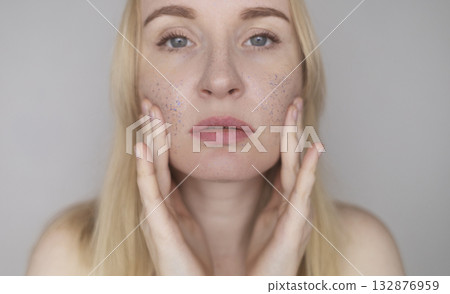 Microplastics in cosmetics. A woman applied a care cream to her skin, now it is covered with plastic particles and microbeads. Cosmetics toxicity concept Microplastics in cosmetics. A woman applied a care cream to her skin, now it is covered with plastic particles and microbeads. Cosmetics toxicity concept 132876959