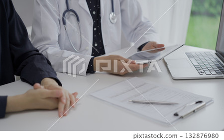 Doctor and a patient in clinic. The female physician is using tablet computer for filling up medication history record form, close up of woman hands. Medicine and science Doctor and a patient in clinic. The female physician is using tablet computer for filling up medication history record form, close up of woman hands. Medicine and science 132876980