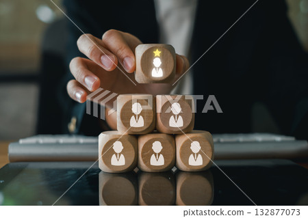 Wooden blocks stacked with a highlighted leader symbol, representing leadership and teamwork in a business environment. 132877073