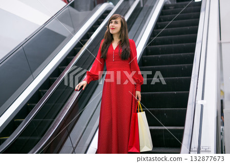 Happy woman with shopping bags on escalator. Shopping mall lifestyle and sales concept. Happy woman with shopping bags on escalator. Shopping mall lifestyle and sales concept. 132877673