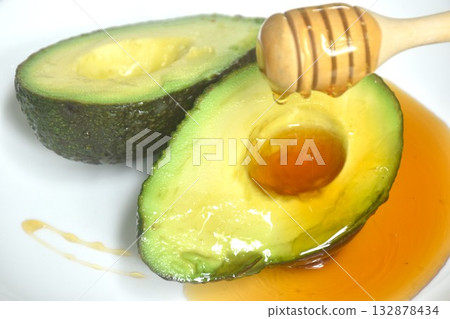 fresh ripe avocado half cutting arranging on plate dressing honey from wooden scoop 132878434