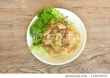 stir fried large noodles with chicken and crispy pickled squid with scent of burning kitchen pan on dish  132878435