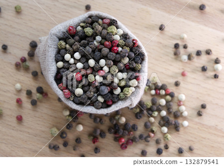 Mixture colored peppers in a canvas sack on wooden kitchen table. Mixture colored peppers in a canvas sack on wooden kitchen table. 132879541