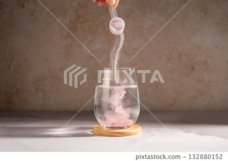 Pouring food supplement powder in glass of water. Collagen, protein powder, vitamins. 132880152