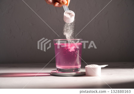 Pouring food supplement powder in glass of water. Collagen, protein powder, vitamins. 132880163