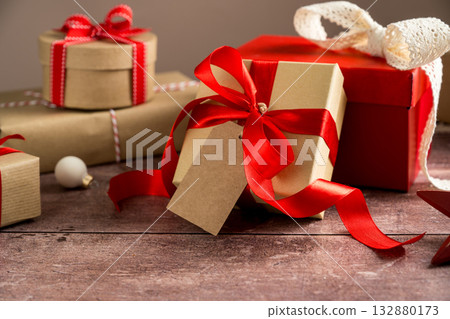 Festive Christmas craft gift boxes with red bows on wooden background 132880173