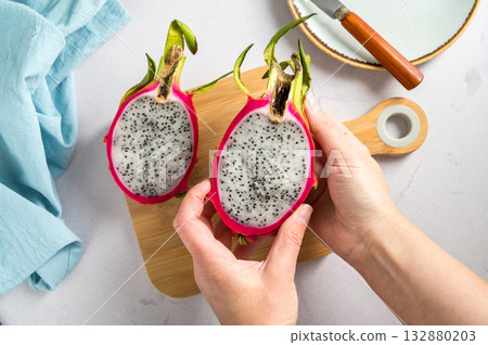 Female hands holding fresh Pitahaya pink dragonfruit. Flat lay. exotic fruit on white background. 132880203