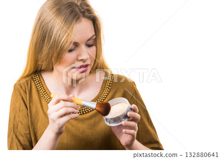 Smiling woman applying face powder 132880641