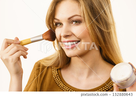 Smiling woman applying face powder 132880643