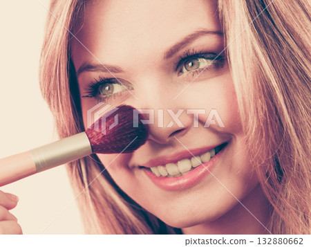Smiling woman holding make up brush 132880662