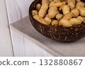 Whole Peanuts in Coconut Bowl on Wooden Table Close-up 132880867