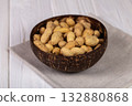 Whole Peanuts in Coconut Bowl on Wooden Table Close-up 132880868