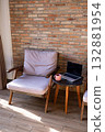 Cozy armchair and laptop on side table next to brick wall. 132881954