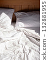 Unmade bed with white linen in sunlight. Cozy morning scene. 132881955