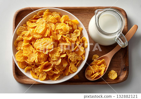 Minimalist breakfast. Top view of a tray of cornflakes on a bowl and milk jug on a white background. Classic breakfast. Minimalist breakfast. Top view of a tray of cornflakes on a bowl and milk jug on a white background. Classic breakfast. 132882121