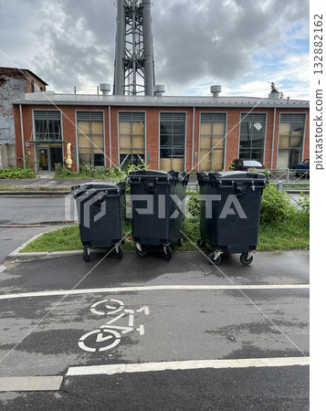Black plastic garbage cans stand on the street 132882162