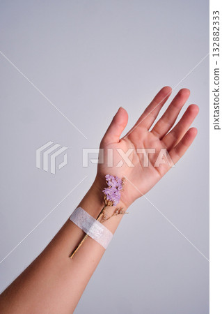 Hand healing with purple flower and bandage 132882333