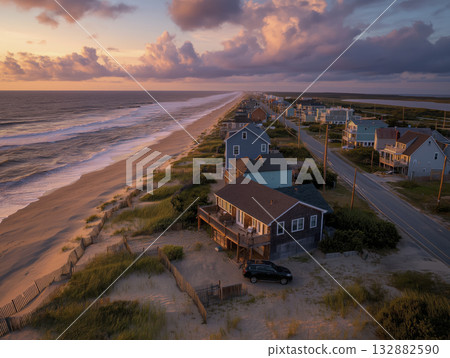 Coastal beach house sunset ocean waves dune grass shoreline aerial view colorful town 132882590