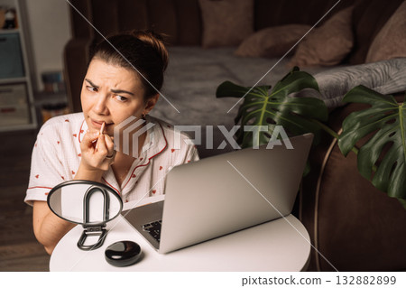 Woman applying lip liner before online meeting at home 132882899