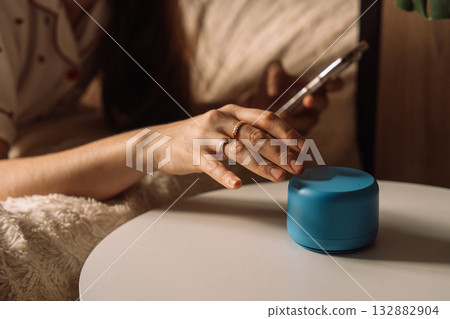 Hand reaching to interact with blue AI smart speaker Hand reaching to interact with blue AI smart speaker 132882904