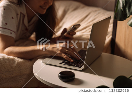 Woman using laptop and phone with AI home assistant Woman using laptop and phone with AI home assistant 132882916