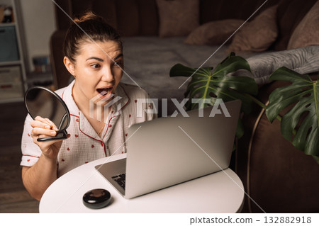 Surprised woman reacting during home video chat session 132882918