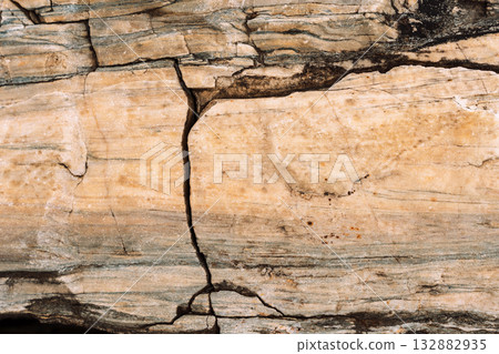 Beige stone slab with vertical crack and banded inclusions 132882935