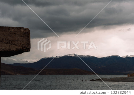 Storm clouds over mountain reservoir, concrete edge framing 132882944