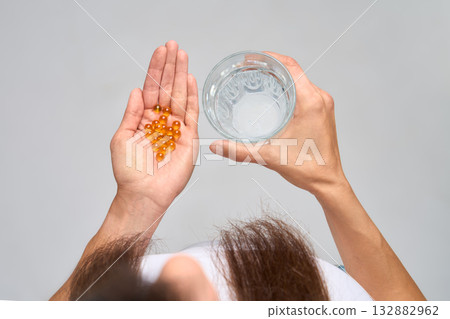 Top view of woman holding glass of water and omega-3 capsules  132882962