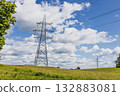 High voltage power lines and steel transmission towers across rural meadow 132883081